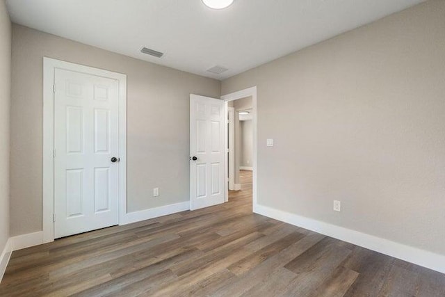 unfurnished bedroom featuring wood finished floors, visible vents, and baseboards