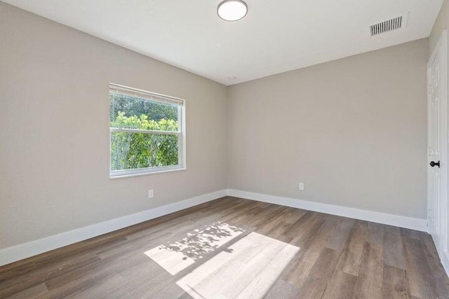 unfurnished room with wood finished floors, visible vents, and baseboards