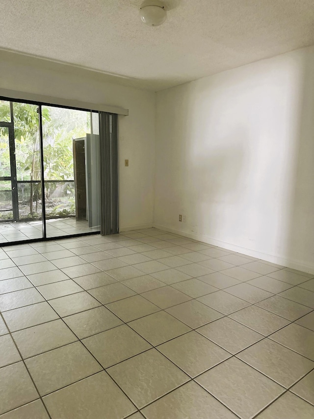 unfurnished room featuring a textured ceiling, light tile patterned floors, and baseboards