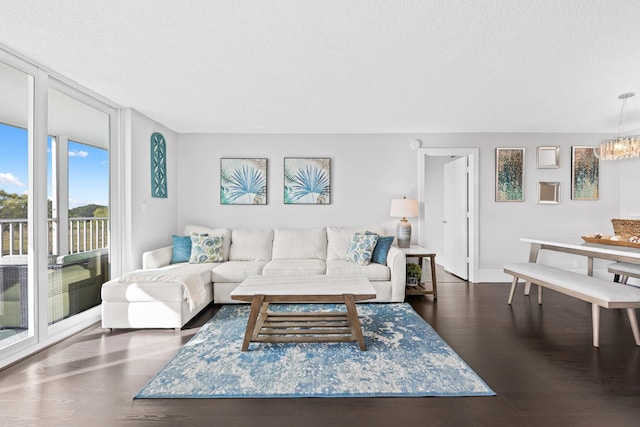 living area featuring a textured ceiling, a chandelier, a wall of windows, and wood finished floors