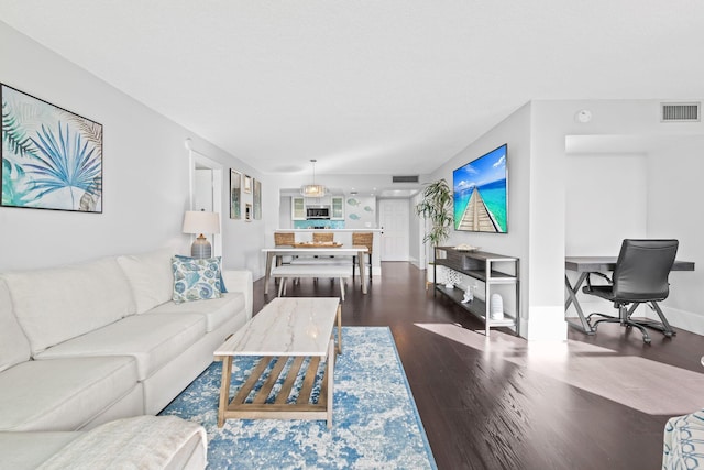 living room with wood finished floors, visible vents, and baseboards