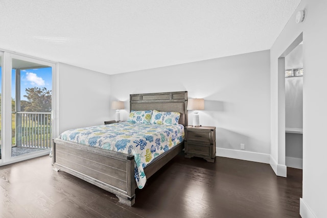 bedroom with baseboards, dark wood-type flooring, access to outside, a textured ceiling, and floor to ceiling windows