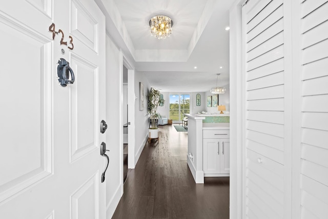 entrance foyer featuring a chandelier, recessed lighting, baseboards, dark wood-style floors, and a tray ceiling