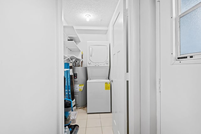 laundry room featuring electric water heater, a textured ceiling, stacked washing maching and dryer, laundry area, and tile patterned floors