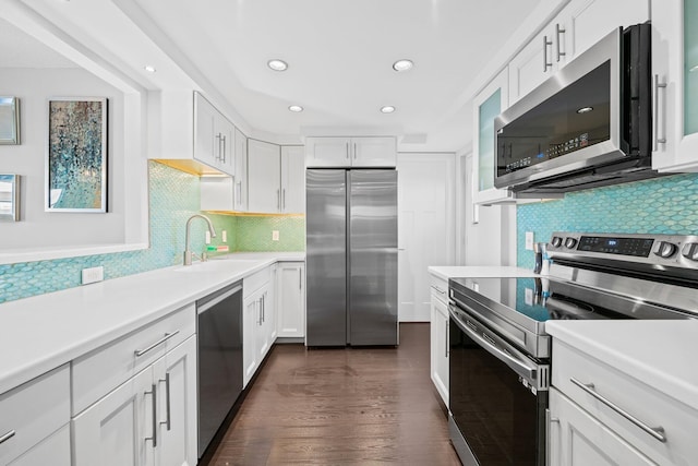 kitchen with dark wood-style flooring, light countertops, appliances with stainless steel finishes, white cabinetry, and a sink