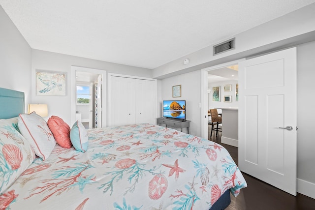 bedroom with dark wood finished floors, a closet, visible vents, a barn door, and baseboards