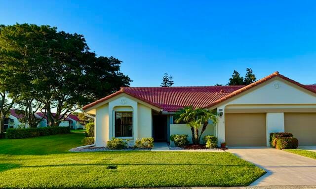 view of front of property featuring a tile roof, stucco siding, concrete driveway, a front yard, and a garage