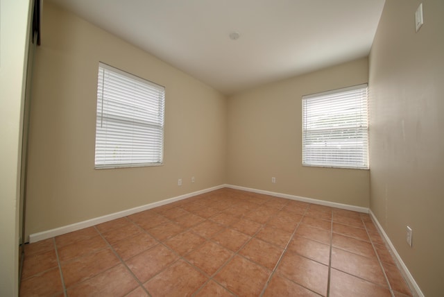 spare room featuring light tile patterned floors and baseboards