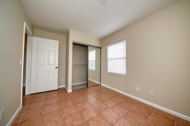 unfurnished bedroom featuring light tile patterned floors, baseboards, and a closet