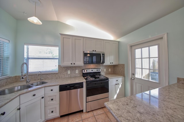 kitchen featuring light tile patterned floors, a sink, stainless steel appliances, vaulted ceiling, and backsplash