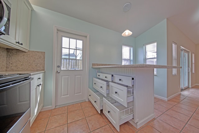 kitchen with stainless steel microwave, black electric range, light tile patterned floors, and light countertops