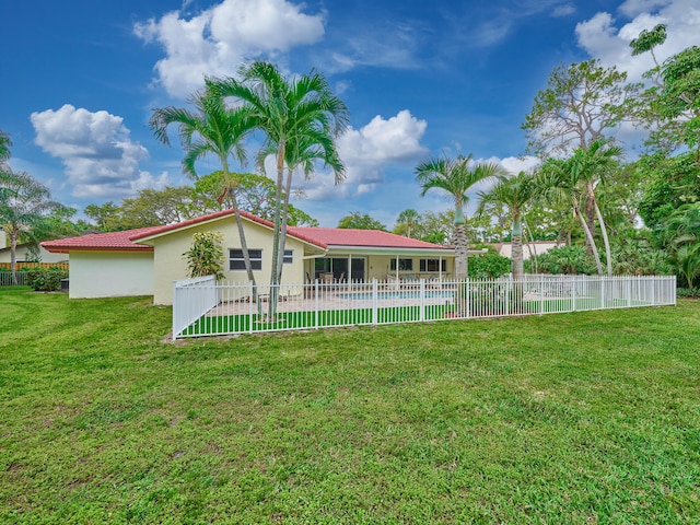 rear view of house featuring a yard, fence, and stucco siding