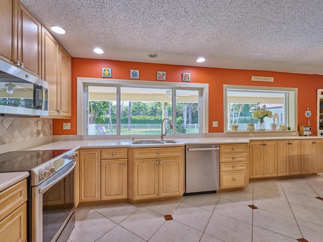 kitchen with light tile patterned flooring, stainless steel appliances, a sink, light countertops, and decorative backsplash