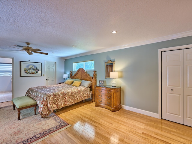 bedroom with baseboards, a textured ceiling, light wood-type flooring, and crown molding