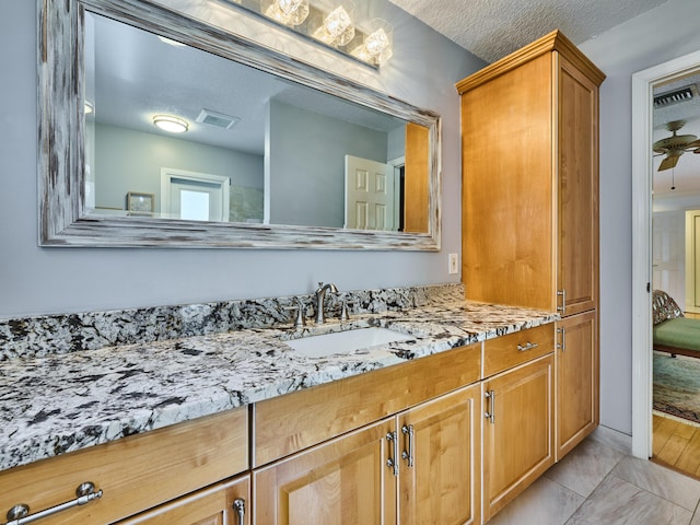 bathroom with a ceiling fan, visible vents, a textured ceiling, and vanity