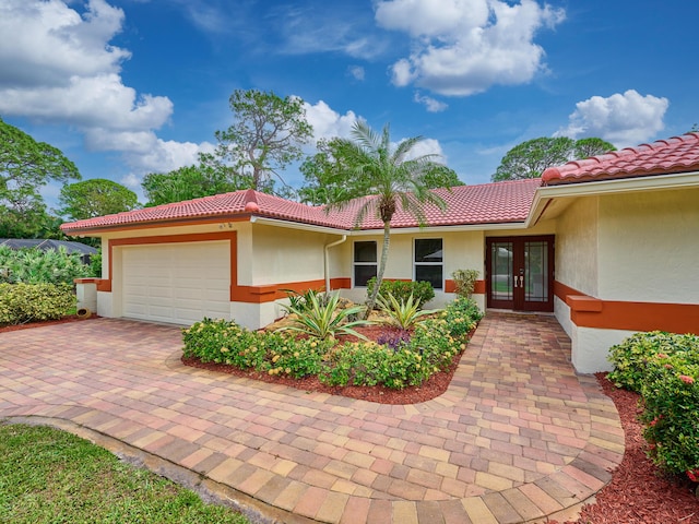 view of front of home featuring a garage, french doors, a tiled roof, and stucco siding