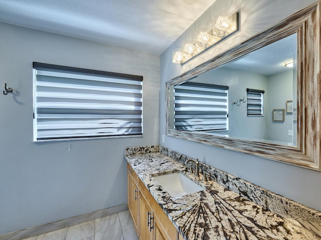 bathroom featuring a textured ceiling, vanity, and baseboards