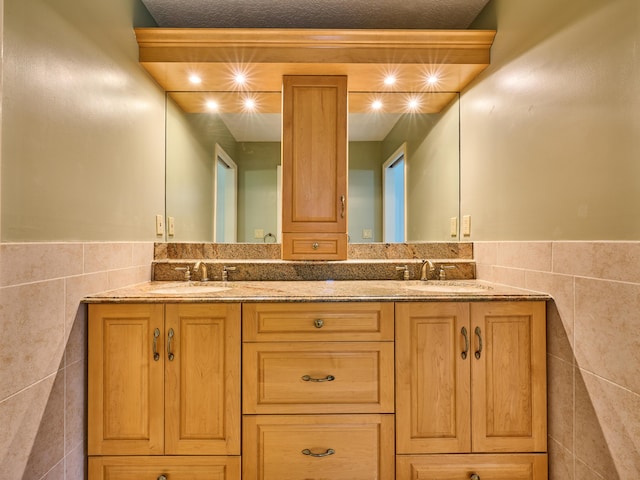 full bath with a sink, tile walls, and double vanity