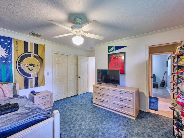 carpeted bedroom featuring visible vents, a ceiling fan, ornamental molding, a textured ceiling, and a closet