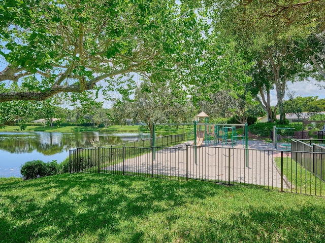 community jungle gym with a water view, fence, and a yard