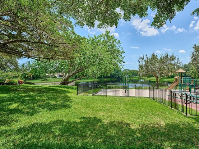 view of yard featuring playground community, fence, and a water view