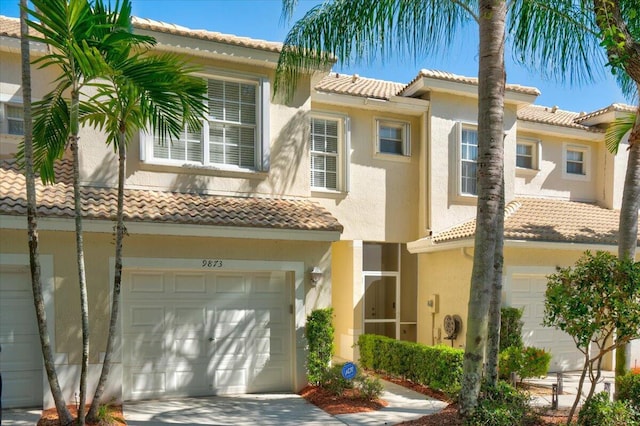 mediterranean / spanish home featuring a tiled roof, an attached garage, and stucco siding