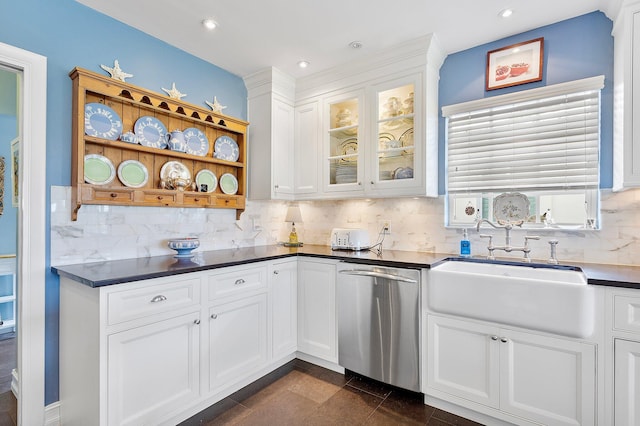 kitchen featuring decorative backsplash, white cabinets, dishwasher, dark countertops, and a sink