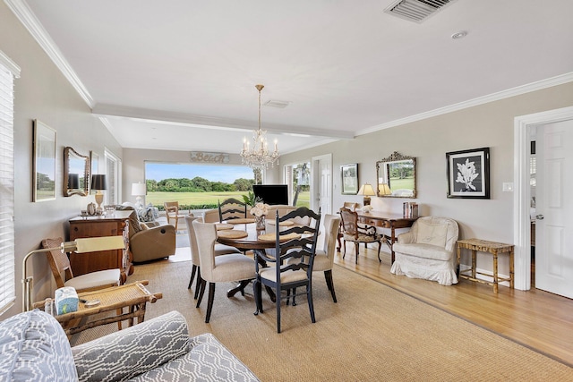 dining room with light wood finished floors, visible vents, crown molding, and an inviting chandelier