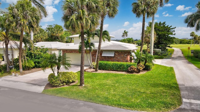 view of front of home featuring a front yard, concrete driveway, and brick siding