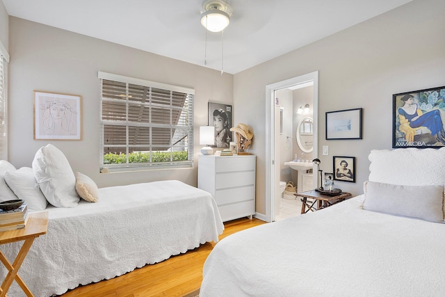 bedroom featuring a sink, connected bathroom, a ceiling fan, and wood finished floors