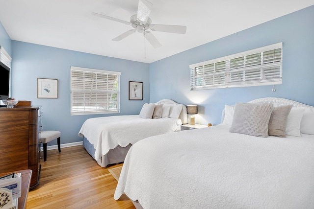 bedroom featuring light wood finished floors, a ceiling fan, and baseboards