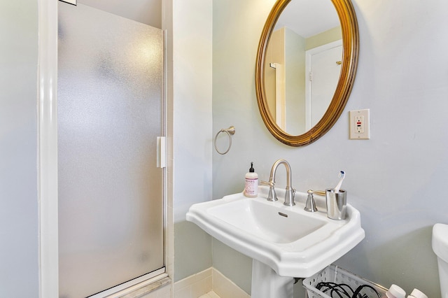 bathroom with a sink, a shower stall, and toilet