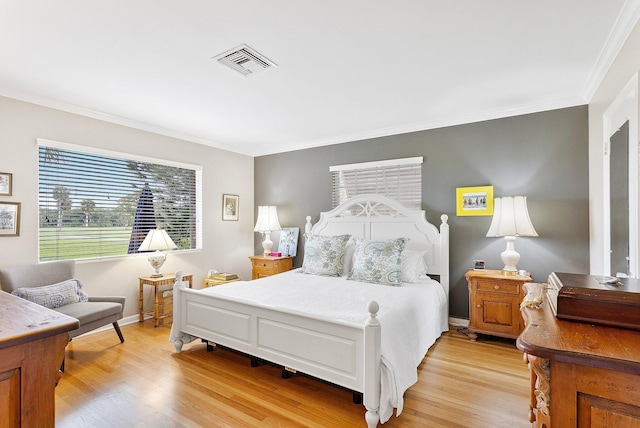 bedroom featuring ornamental molding, visible vents, light wood-style flooring, and baseboards