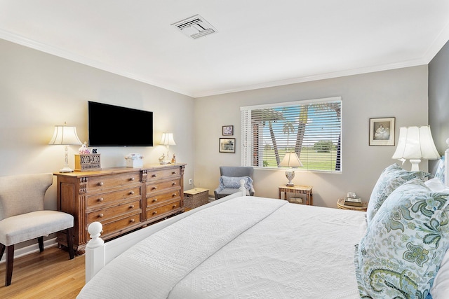 bedroom with light wood-type flooring, visible vents, and ornamental molding