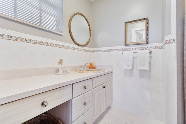 bathroom with a wainscoted wall, vanity, tile walls, and tile patterned floors