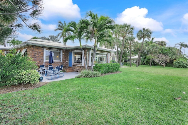 back of property with a patio area, a yard, and brick siding