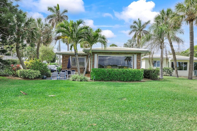 rear view of property featuring brick siding and a lawn