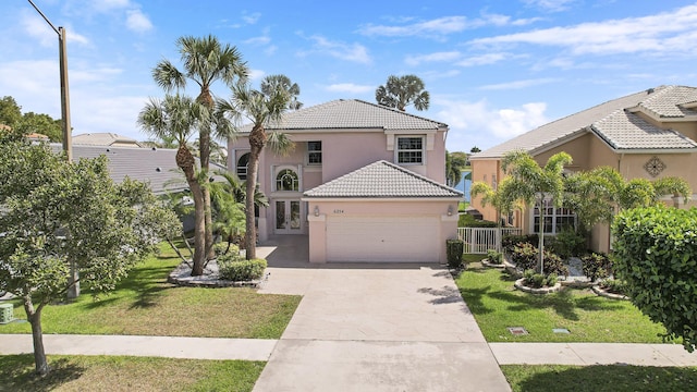 view of front of home featuring an attached garage, a tiled roof, concrete driveway, stucco siding, and a front yard