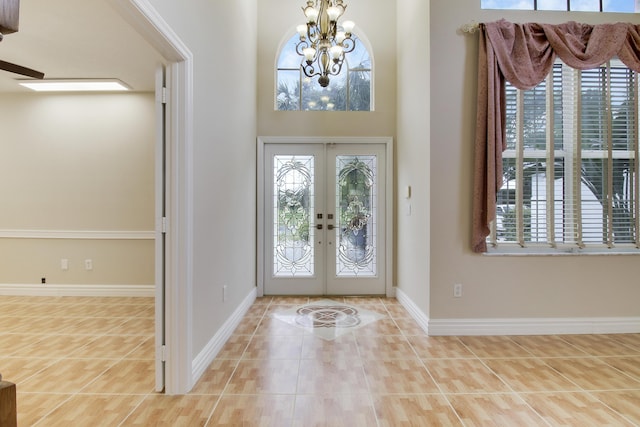 tiled entryway featuring a chandelier, french doors, and baseboards