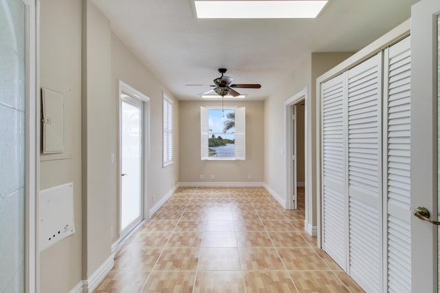 interior space featuring light tile patterned floors, a ceiling fan, and baseboards