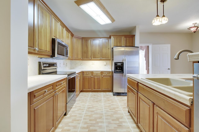 kitchen featuring tile counters, appliances with stainless steel finishes, decorative light fixtures, a sink, and backsplash