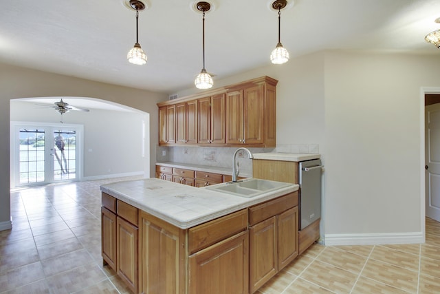 kitchen with arched walkways, ceiling fan, a sink, dishwasher, and tasteful backsplash