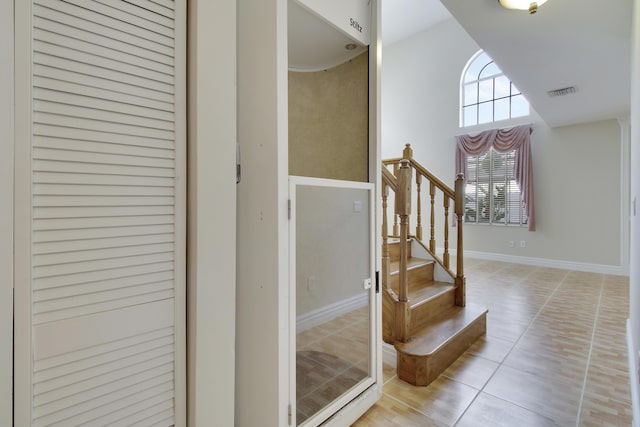 foyer featuring a high ceiling, stairway, visible vents, and baseboards