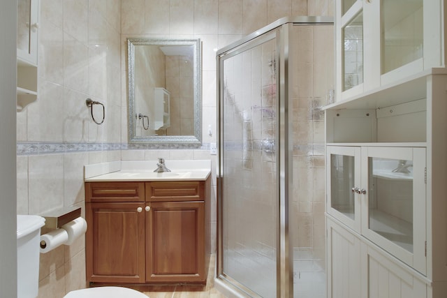 full bathroom with a stall shower, tile walls, toilet, and vanity