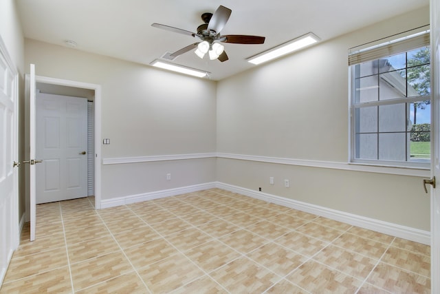 tiled spare room with ceiling fan and baseboards