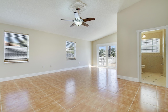 empty room featuring light tile patterned floors, baseboards, lofted ceiling, ceiling fan, and a textured ceiling