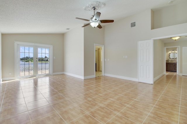 empty room featuring light tile patterned floors, baseboards, visible vents, a ceiling fan, and a textured ceiling