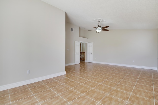 empty room featuring a textured ceiling, light tile patterned flooring, visible vents, a ceiling fan, and baseboards