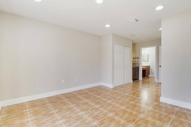 empty room with light tile patterned flooring, baseboards, and recessed lighting