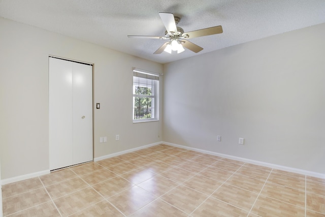 spare room featuring a textured ceiling, ceiling fan, light tile patterned floors, and baseboards